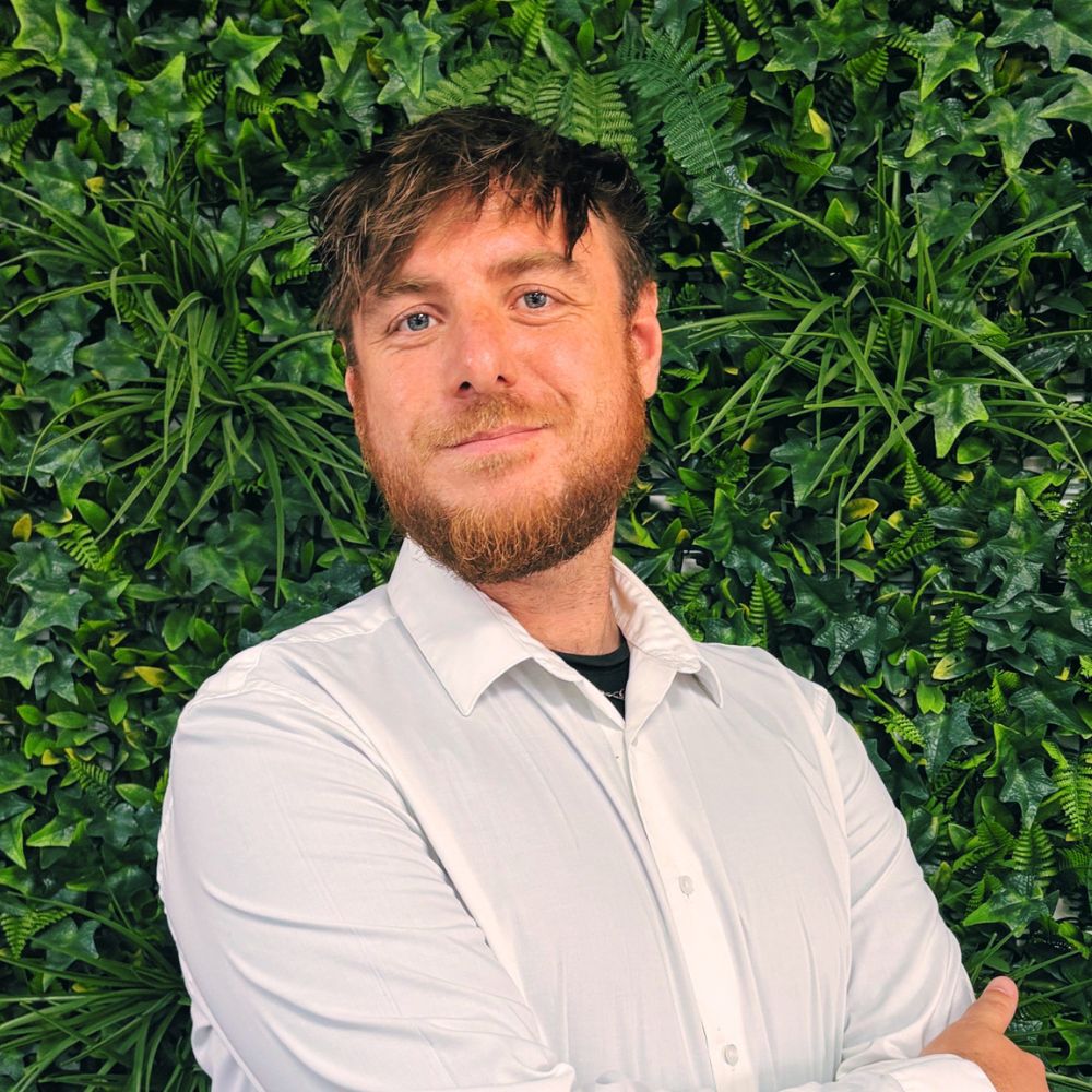 a man smiling at the camera wearing a white shirt